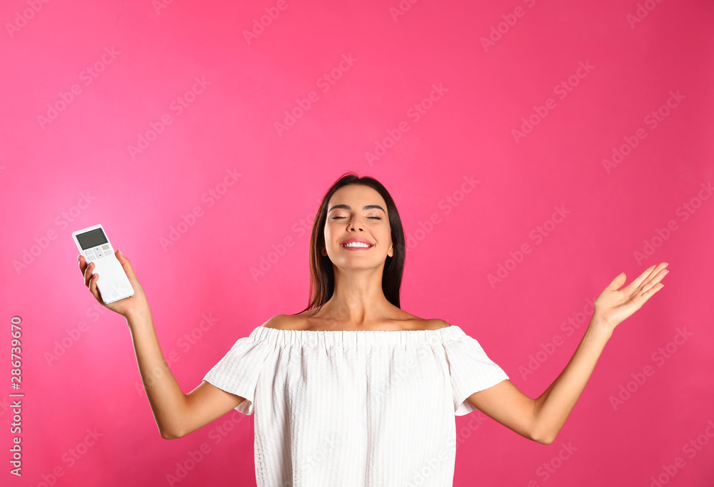 Young woman with air conditioner remote on pink background Young woman with air conditioner remote on pink background