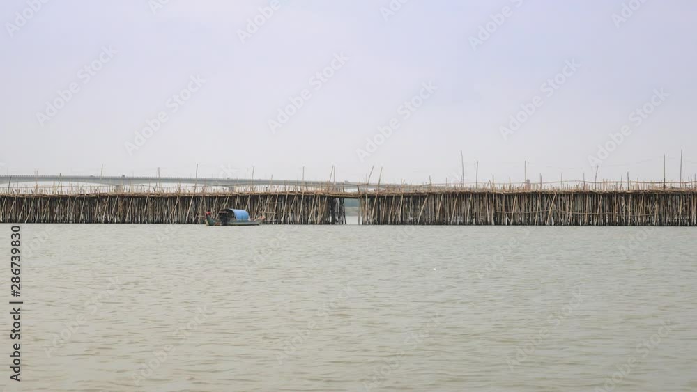 motorbikes crossing a bamboo bridge over the Mekong river and small fishing boat passing under it motorbikes crossing a bamboo bridge over the Mekong river and small fishing boat passing under it