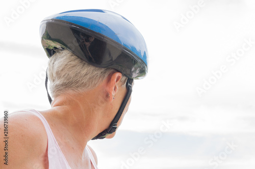 older woman with White hair and blue helmet looking back