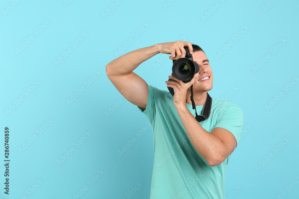 Young professional photographer taking picture on light blue background. Space for text Young professional photographer taking picture on light blue background. Space for text