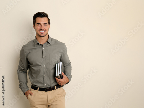 Fotografía Young male teacher with books on beige background. Space for text