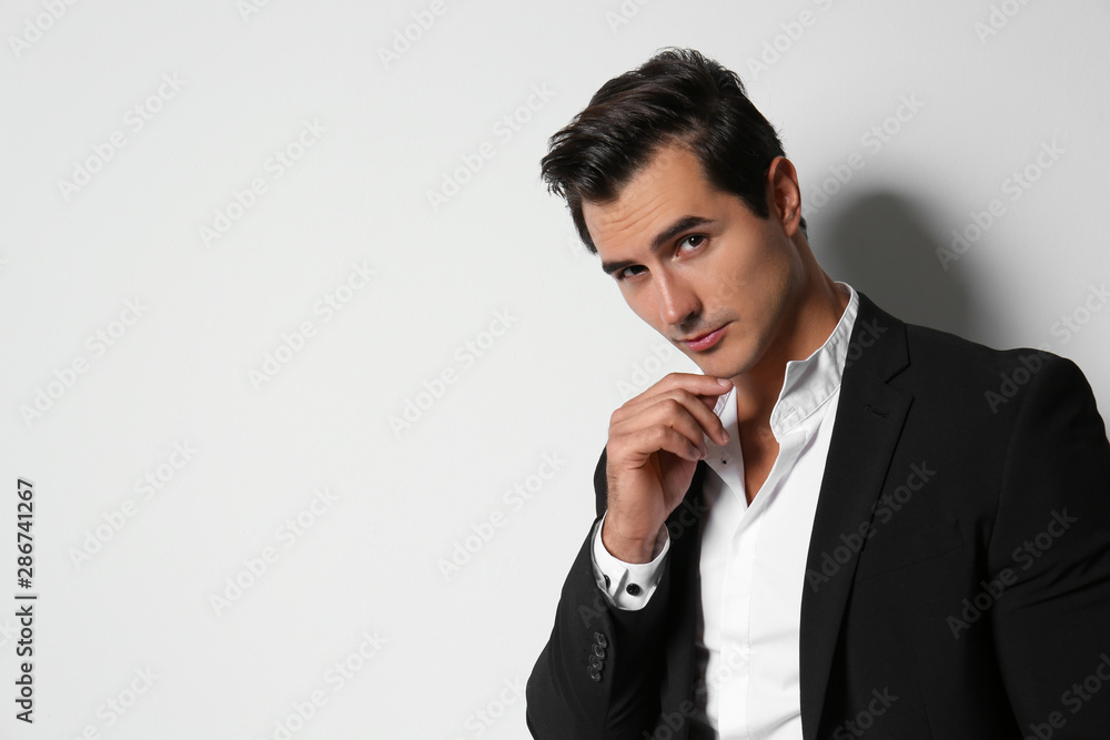 Handsome young man in elegant suit on light beige background. Space for text Handsome young man in elegant suit on light beige background. Space for text