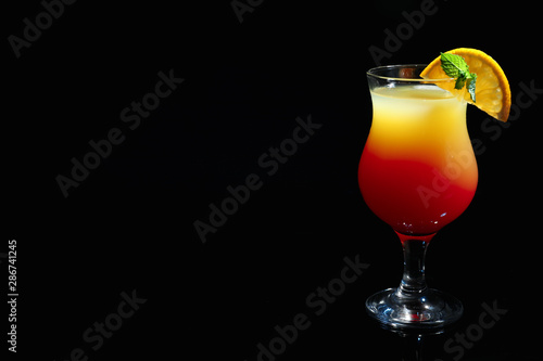 Glass of delicious cocktail Sex on the Beach decorated with orange and mint against black background. Space for text