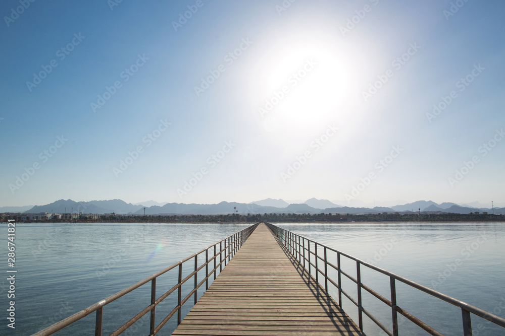 Wooden pier extending into the distance. Mountains on the horizon. Red Sea, Egypt