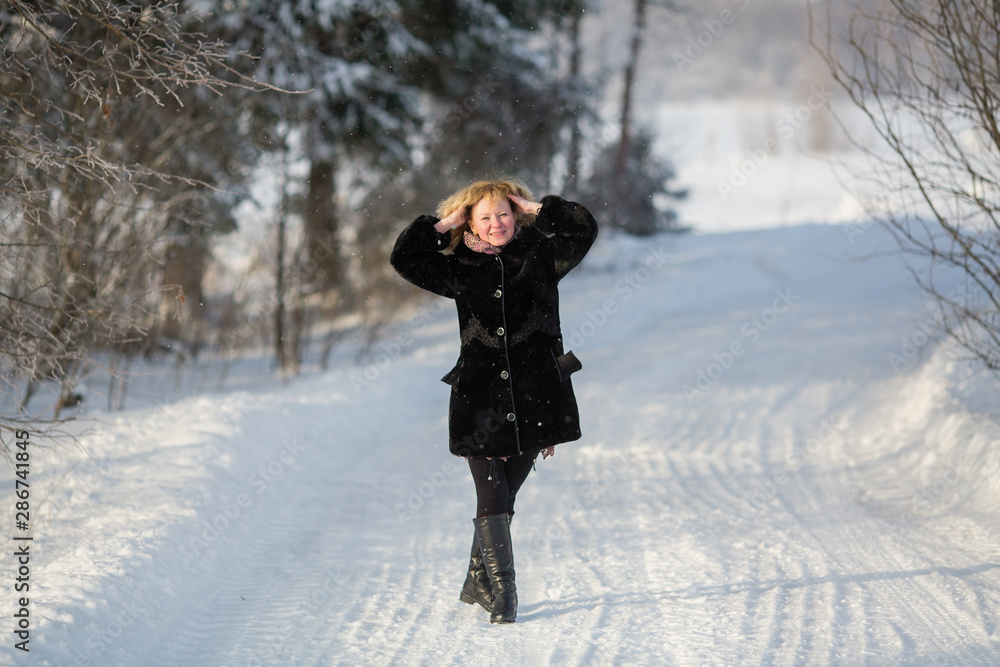 Young russian woman at winter on the snowy road in village.