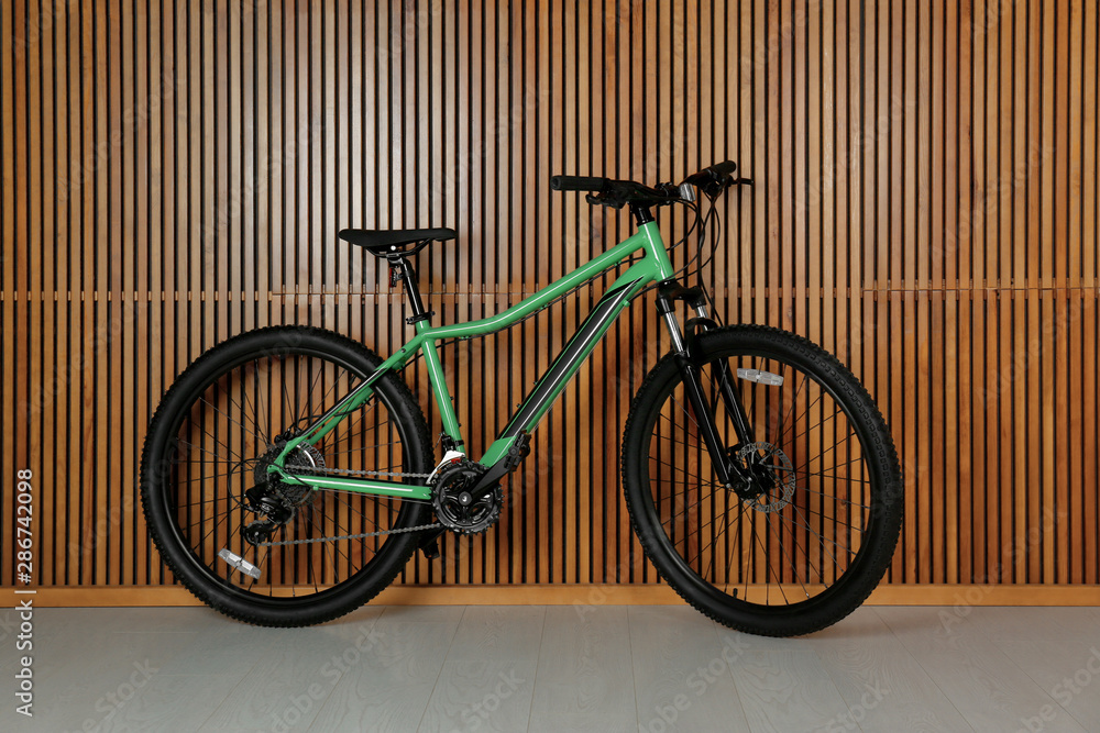 Modern bicycle near wooden wall indoors. Healthy lifestyle Modern bicycle near wooden wall indoors. Healthy lifestyle