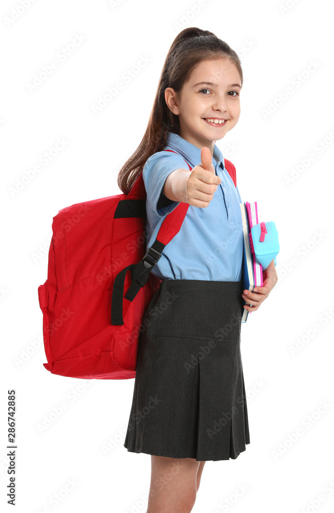 Cute little girl in school uniform with backpack and stationery showing thumbs-up on white background Cute little girl in school uniform with backpack and stationery showing thumbs-up on white background