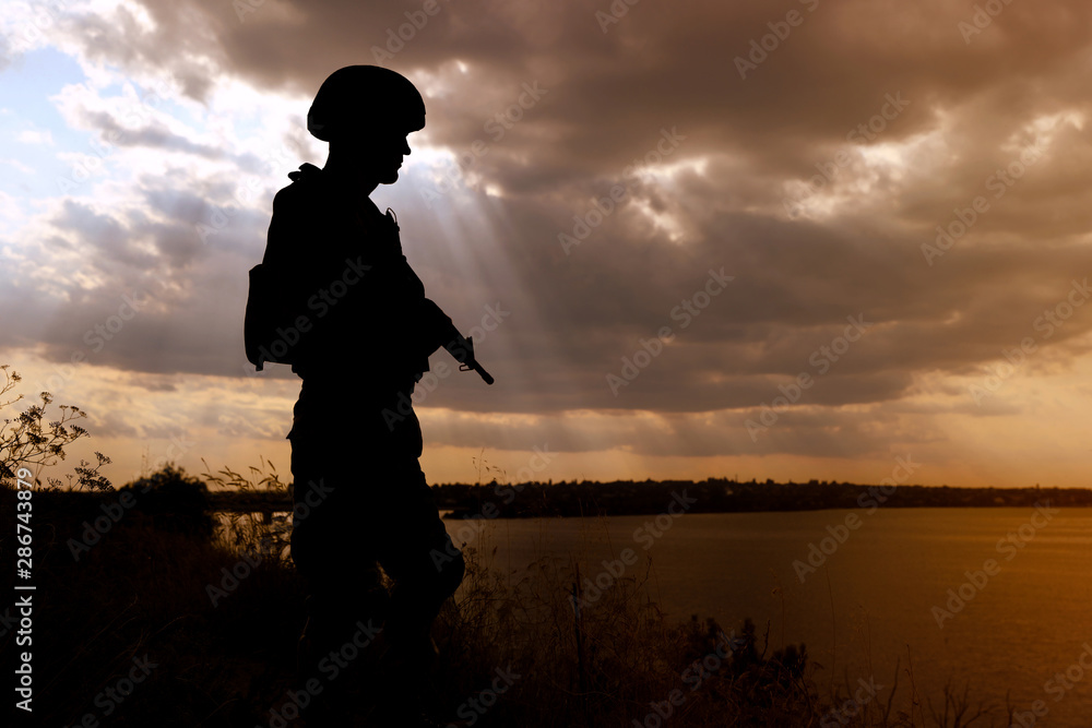 Fototapeta premium Soldier with machine gun patrolling outdoors. Military service