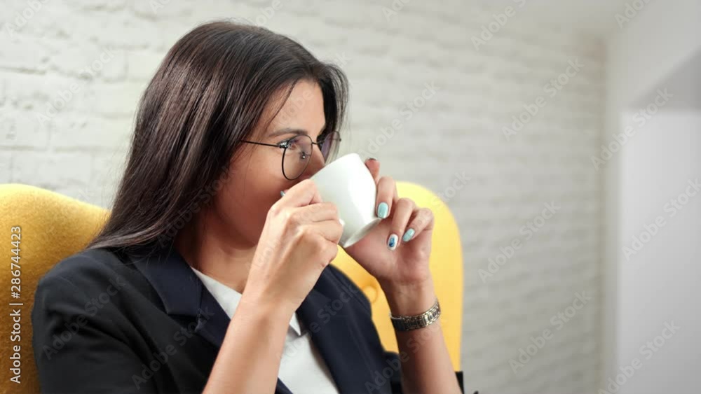 Smiling beautiful informal business woman relaxing drinking coffee at white room background Smiling beautiful informal business woman relaxing drinking coffee at white room background