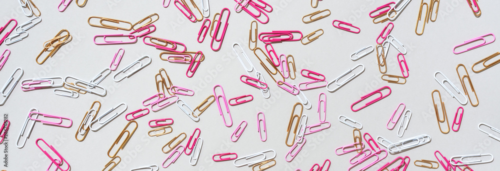 Pattern of multicolored paper clips on grey background. Back to school. Office, business, paperwork, education concept. Banner Pattern of multicolored paper clips on grey background. Back to school. Office, business, paperwork, education concept. Banner