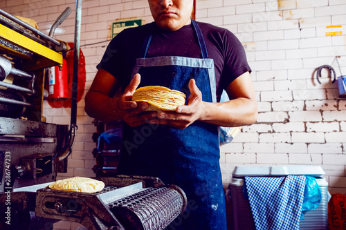 Cut in view of man collecting wheat tortillas from baking machine