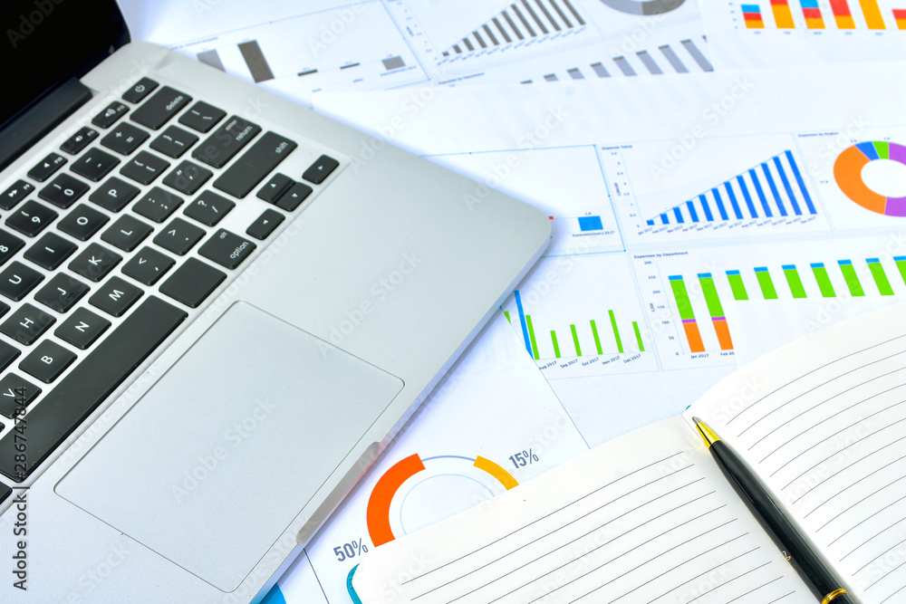 Business and Finances Concepts. Laptop, Notebook with graph and pen Business and Finances Concepts. Laptop, Notebook with graph and pen
