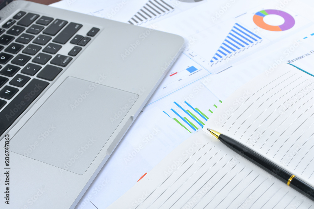 Business and Finances Concepts. Laptop, Notebook with graph and pen Business and Finances Concepts. Laptop, Notebook with graph and pen