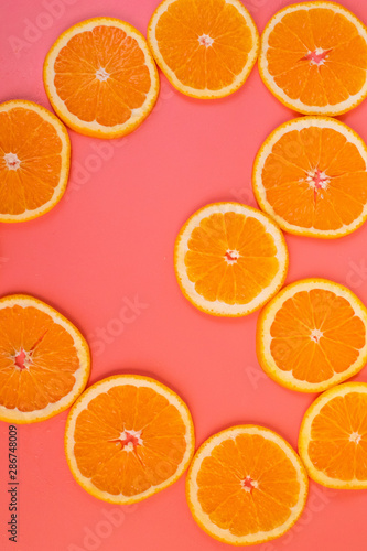 Background of sliced ripe oranges on a pink background vertical.