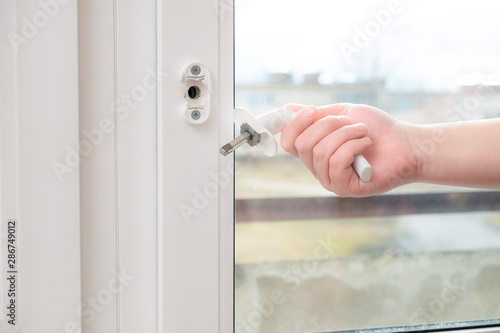 A man holds in his hand a broken doorknob. The door is closed due to negligence and the use of high power or due to defective parts