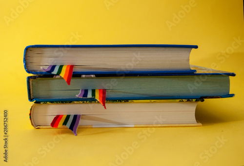 a stack of three books with rainbow ribbon bookmarks is on the table. Concept back to school, freedom, independence