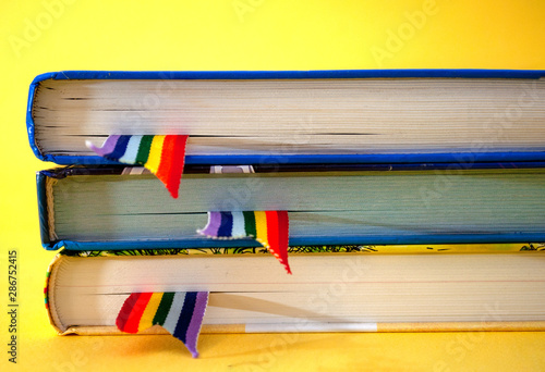 a stack of three books with rainbow ribbon bookmarks is on the table. Concept back to school, freedom, independence