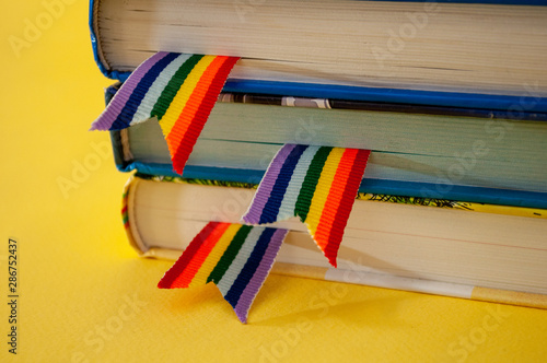 a stack of three books with rainbow ribbon bookmarks is on the table. Concept back to school, freedom, independence