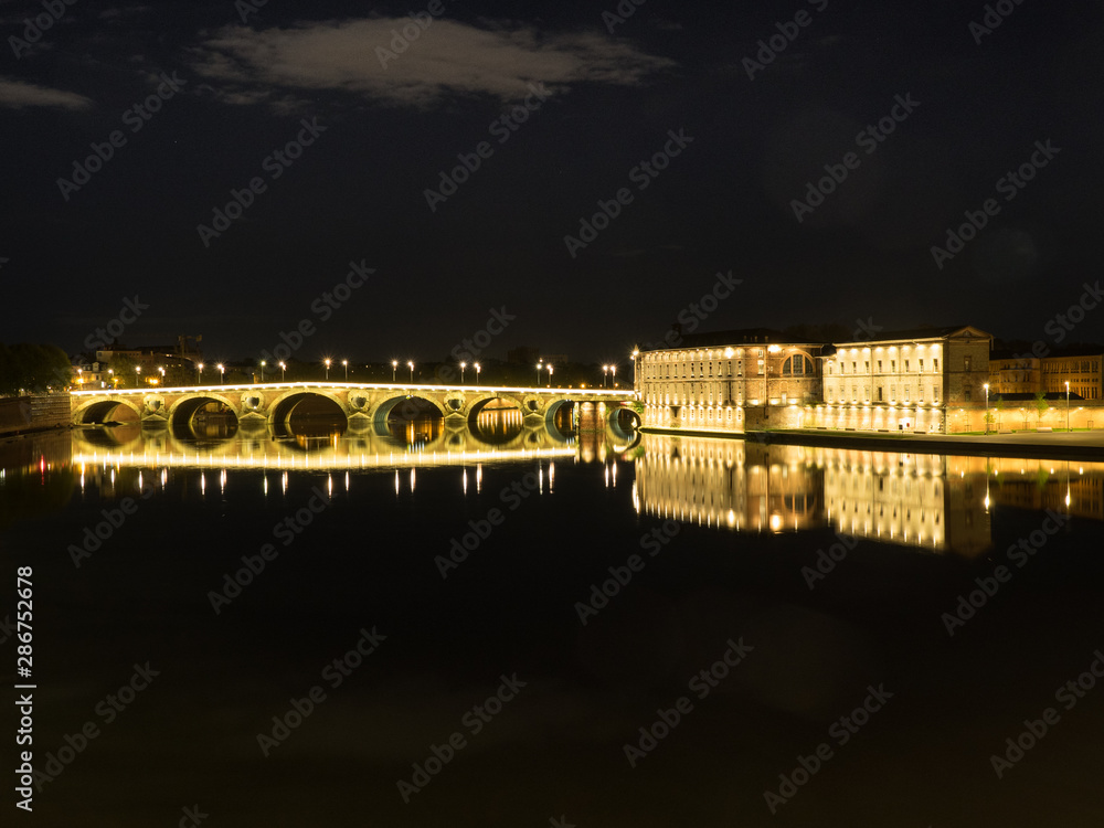night view of the Toulousse bridge over the Garonne river with reflection of the lights in the water
