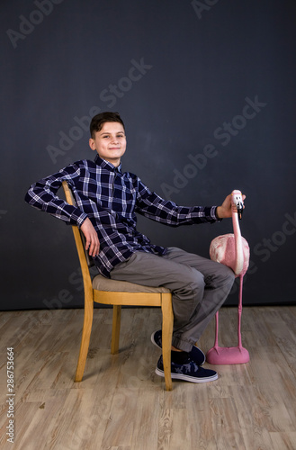 A young man of Slavic appearance and a toy pink flamingo. Shooting in the studio, plain gray background.