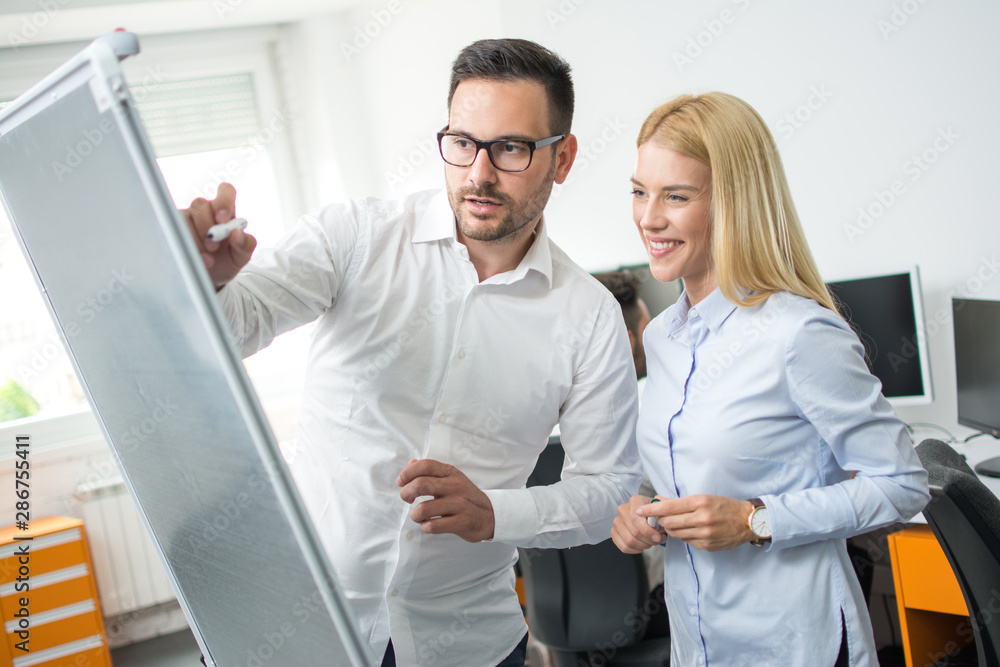 Business team of two beautiful business people using flip chart board in office