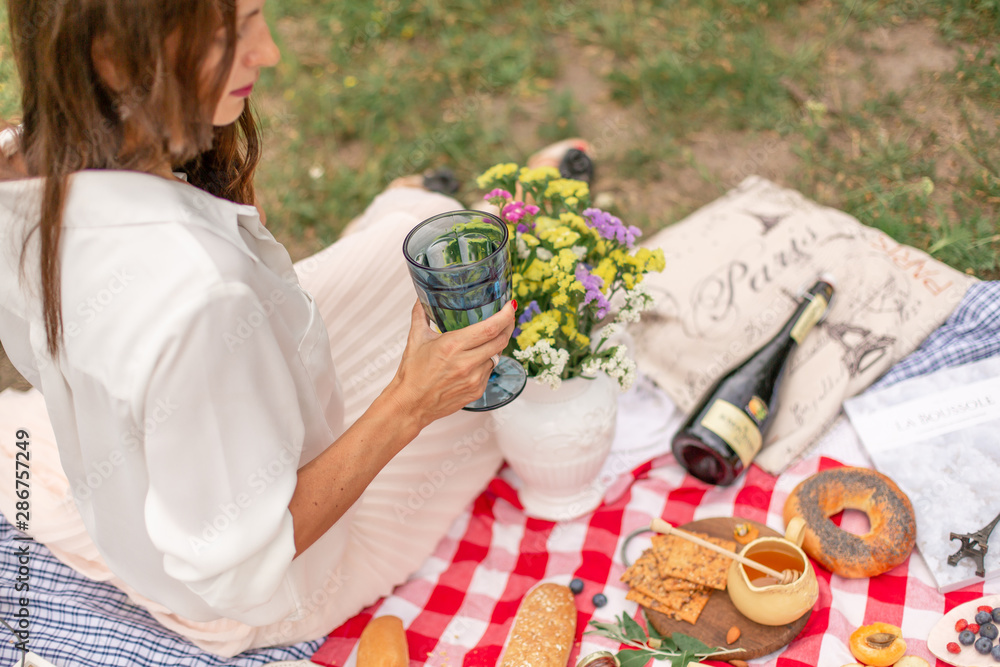 Fototapeta premium Young brunette woman enjoy outdoor picnic on green lawn.