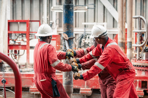 Employees holding chain attached to a pipe photo