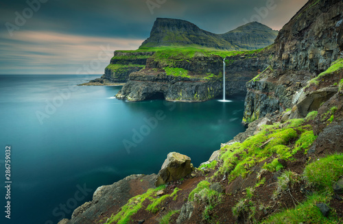 view to green hills and waterfall in village Gasadalur on on Faroe island. Big size.