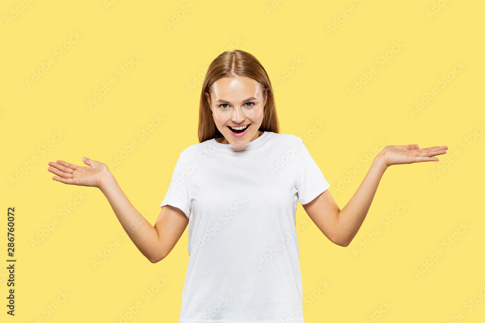 Caucasian young woman's half-length portrait on yellow studio background. Beautiful female model in white shirt. Concept of human emotions, facial expression. Showing an empty bar and smiling. Caucasian young woman's half-length portrait on yellow studio background. Beautiful female model in white shirt. Concept of human emotions, facial expression. Showing an empty bar and smiling.