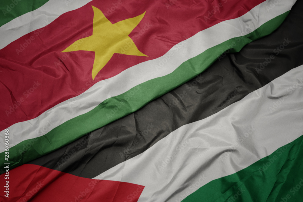 waving colorful flag of palestine and national flag of suriname.