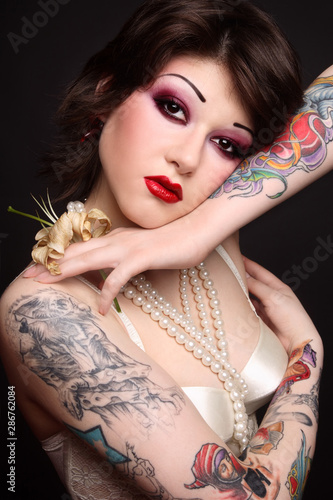 Vintage style portrait of beautiful punk woman with tattoos and fancy makeup