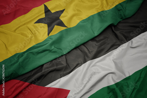 waving colorful flag of palestine and national flag of ghana.