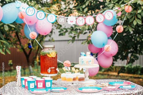 Boy or girl cake and different treats for baby shower party on table outdoors © Olga