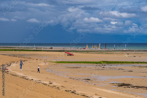 Luc-Sur-Mer, France - 08 12 2019:  View of the beach from with groups of people and sailing boats © Franck Legros