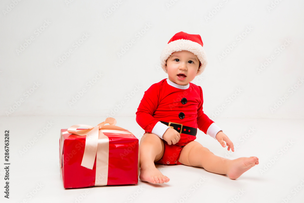 two toddlers in Santa Claus costumes with gift box on white isolate background two toddlers in Santa Claus costumes with gift box on white isolate background
