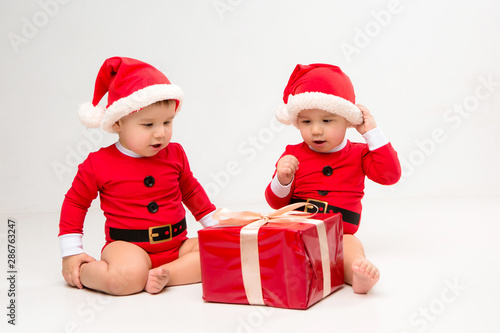  two toddlers in Santa Claus costumes with gift box on white isolate background