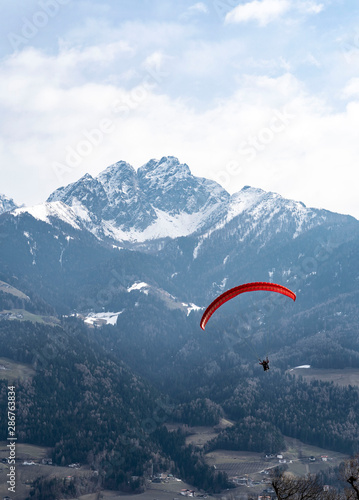 Two people flying with a Tandem and enjoying the freedom, high up in the sky with a few clouds and mountains covered in snow in the background