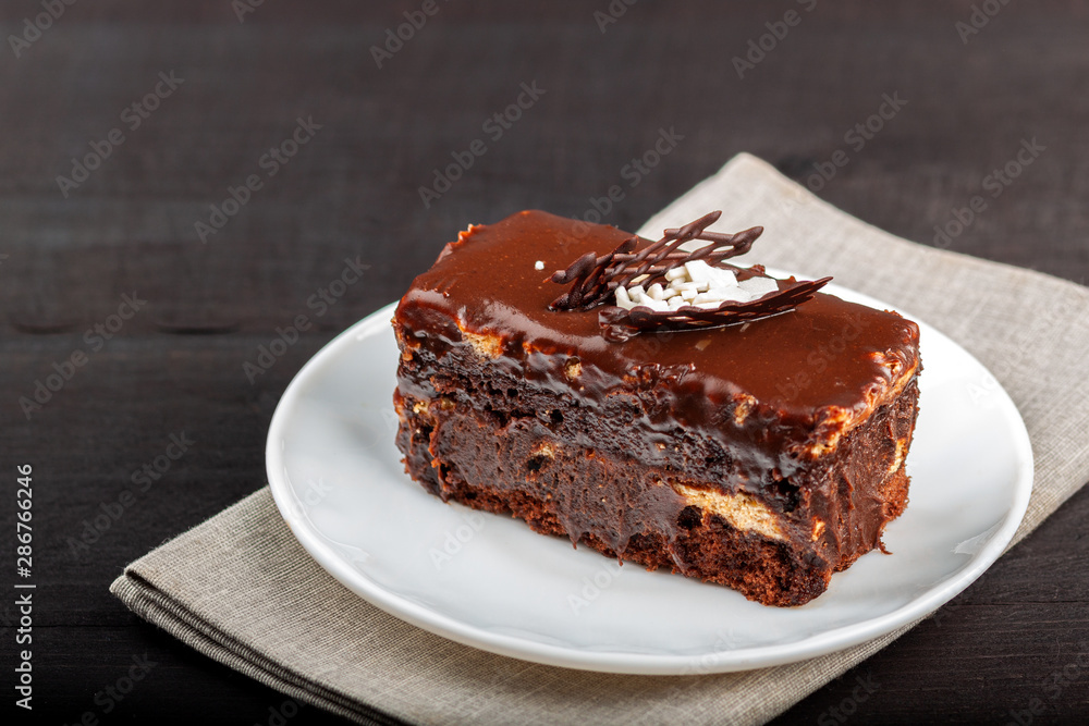Dish with a slice of chocolate cake stands on a wooden table Dish with a slice of chocolate cake stands on a wooden table