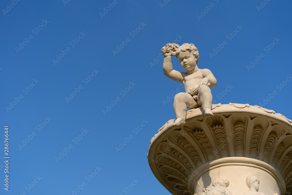 Obraz premium A boy statue in a public garden looks down.