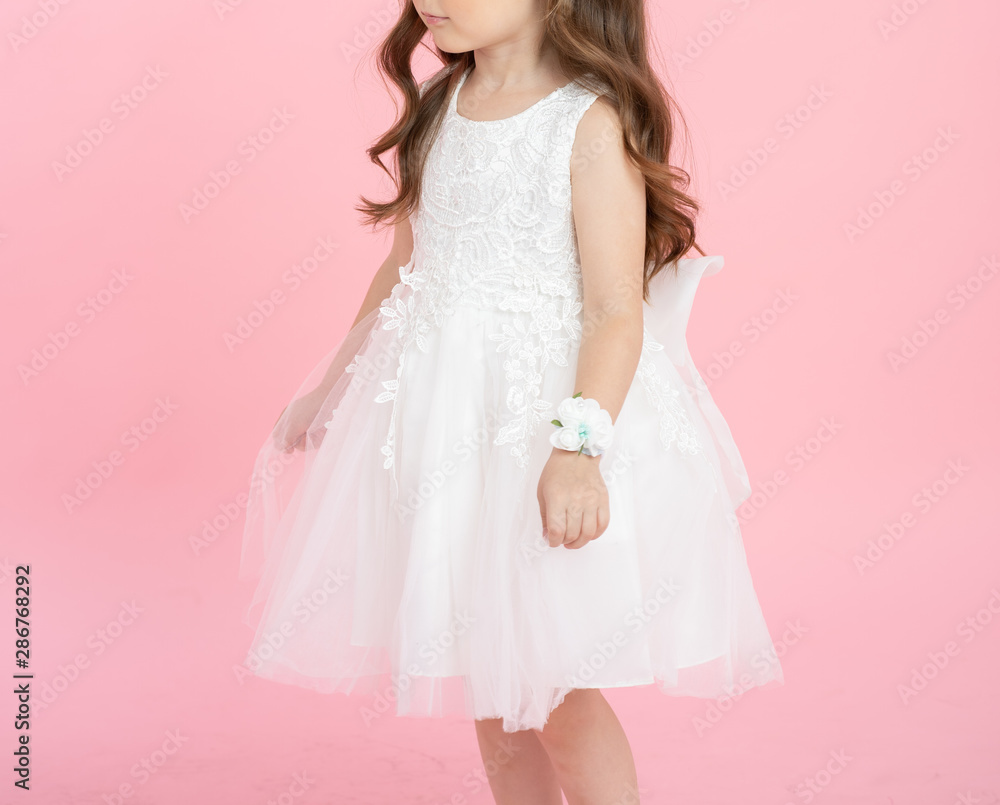 Little cute girl with beautiful long curly hair in white princess dress, isolated on pink background. Fashion, color concept. Side view. Little cute girl with beautiful long curly hair in white princess dress, isolated on pink background. Fashion, color concept. Side view.