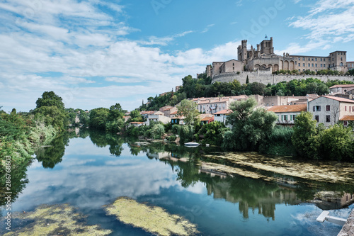 Old medieval town rounded by green forest and reflected in the water. Béziers, France