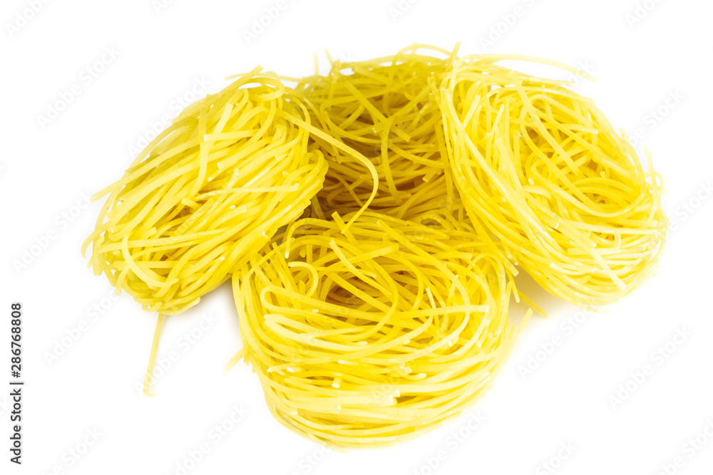 Raw yellow italian vermicelli isolated on white background. Ribbon noodles, long rolled macaroni or uncooked spaghetti isolated