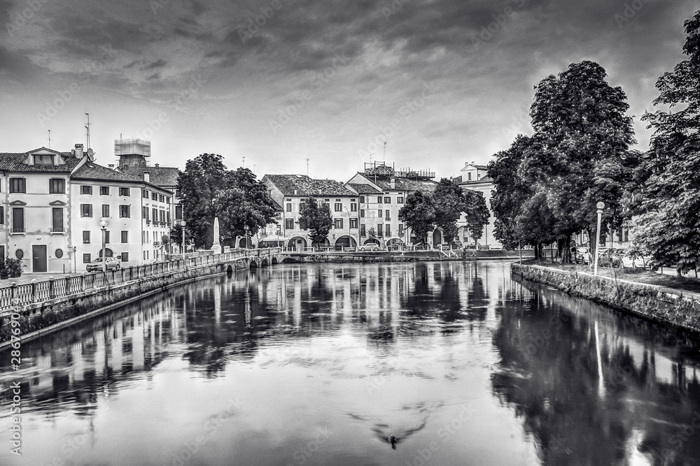 Landscape view of the river Sile flowing through the city. Buildings around. Black and White. Treviso, Veneto, Italy.