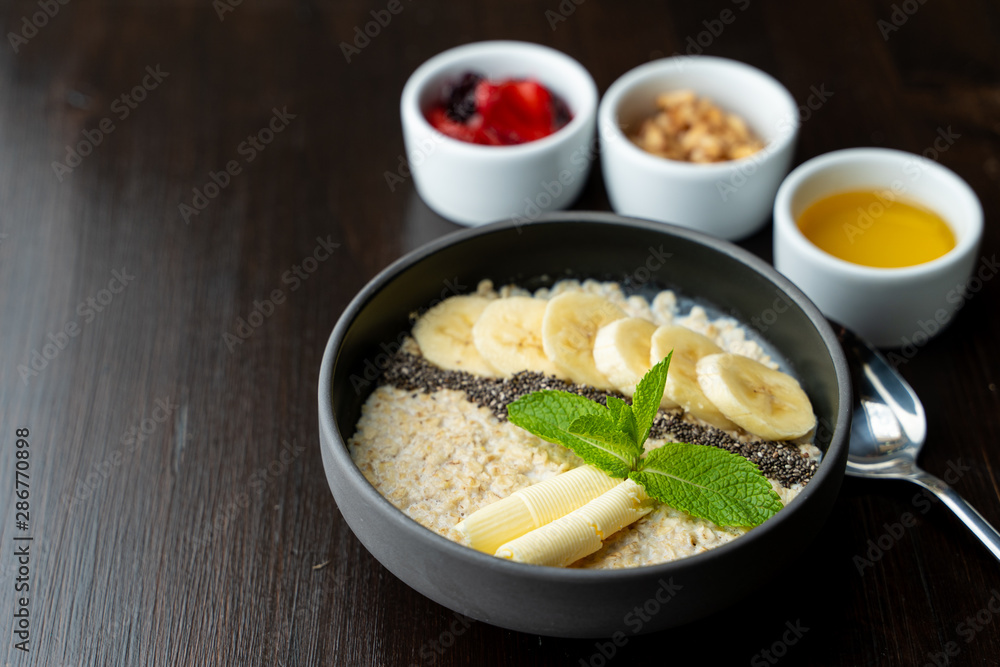 Close up of whole grain porridge with different toppings, served on dark table as a healthy substantial breakfast Close up of whole grain porridge with different toppings, served on dark table as a healthy substantial breakfast