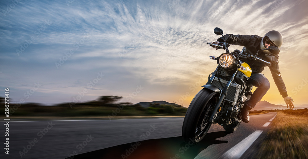 Fototapeta człowiek na motocyklu na drodze. zabawy z jazdy pustą drogą podczas wycieczki motocyklowej. miejsce na Twój indywidualny tekst.