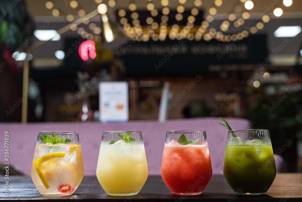 Row of multicolored herbal and fruit tea with lemon, strawberry, matcha and berries, placed on a blurred cafe background