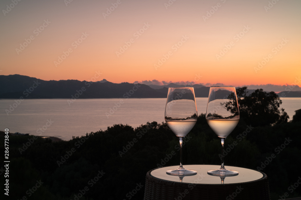 Obraz premium Two glasses of Wine, during a romantic sunset over the sea