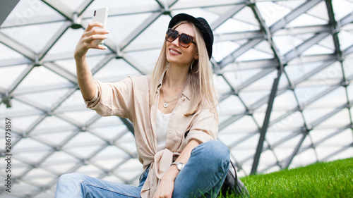 Beautiful young european woman say hello to her friend by smartphone. Happy woman traveller-blogger communicate with her subscribers by the video camera at the phone. Perfect pretty woman make selfie