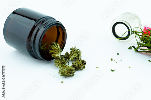 Black glass medical vial of cannabis buds inside and glass smocking pipe on the background. Medical cannabis concept