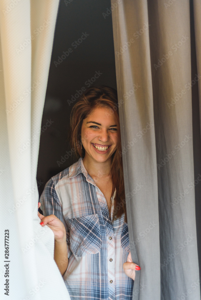 smiling young woman between curtains